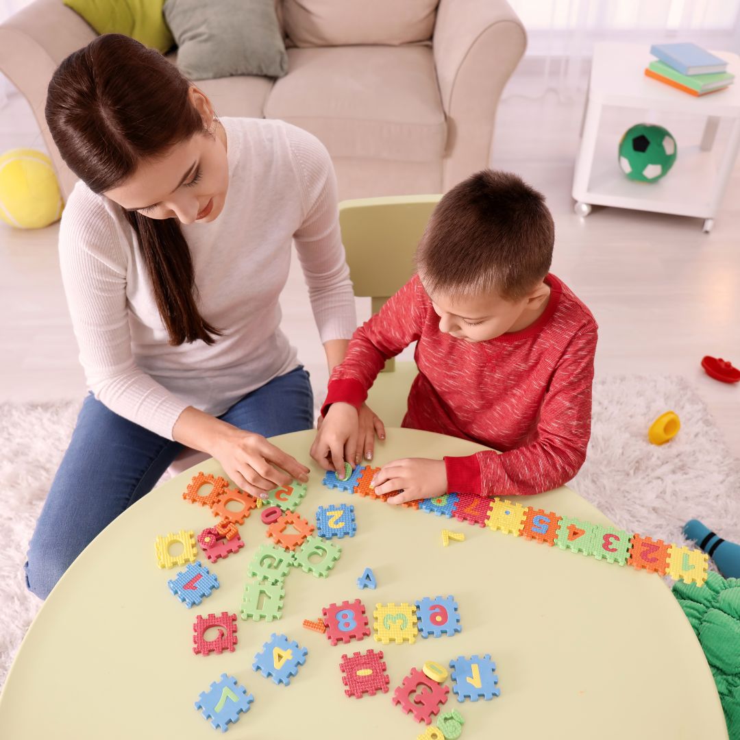 A woman and young boy play with a puzzle