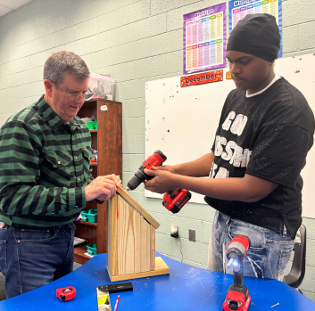 Bill works with a student on a birdhouse