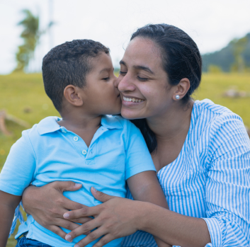 A Latino boy kisses his smiling mother on the cheek