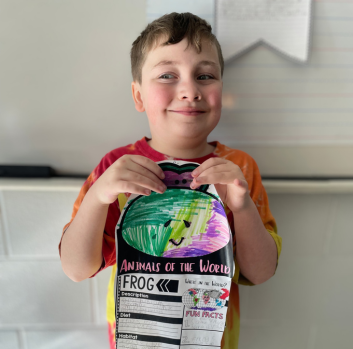 A student smiles with his book project