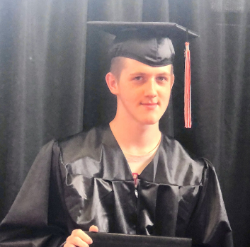 Headshot of a white male wearing a black graduation cap with a light red tassel in front of a black background