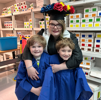 Miriam, Gabriel and Kevin smile at the camera in their graduation gowns