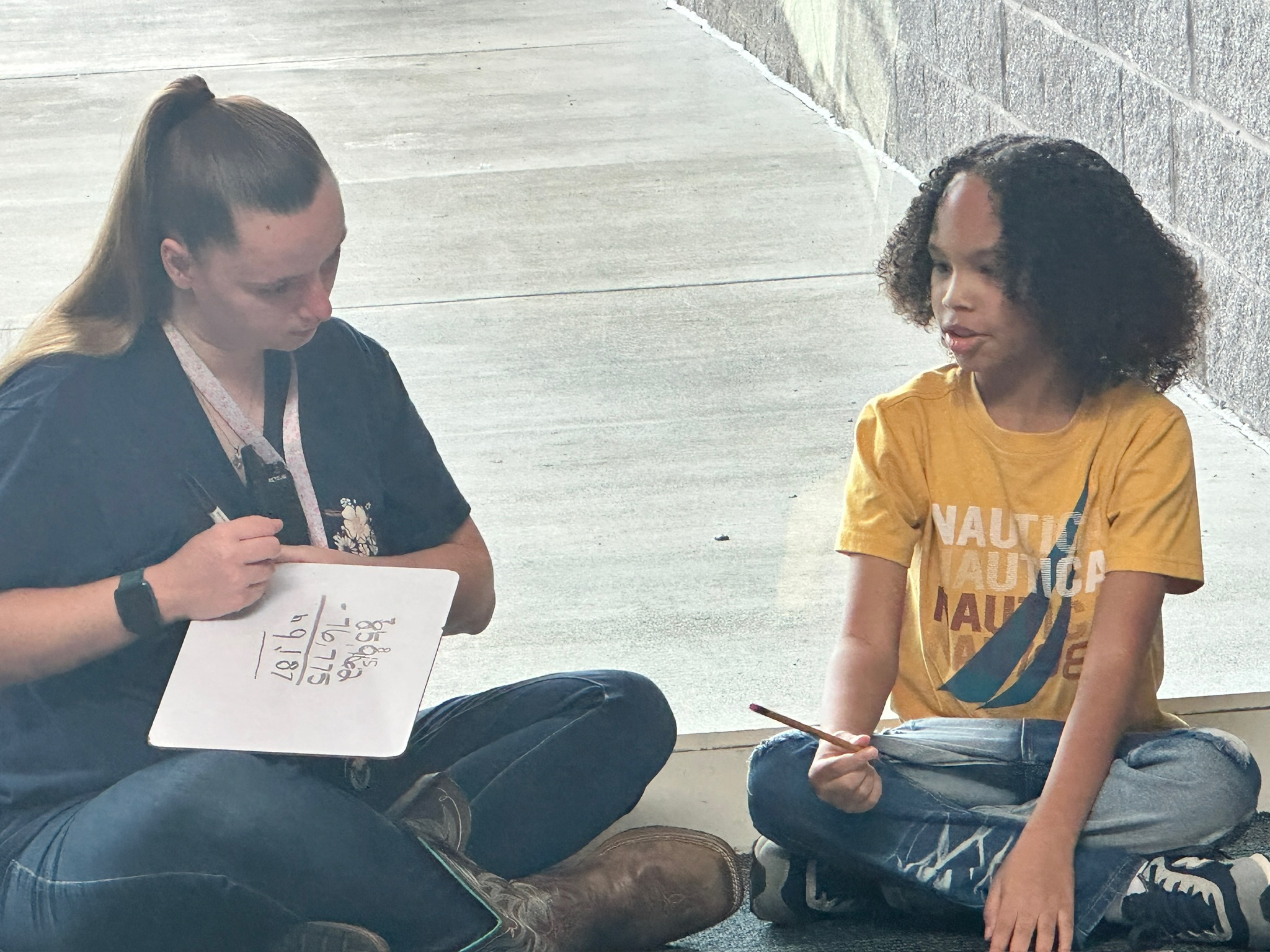A teacher helps a student in the hallway