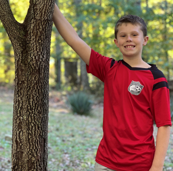 Shaun stands outside next to a tree
