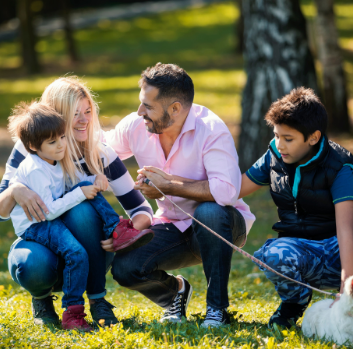 A mother and father smile together with their two sons at a park