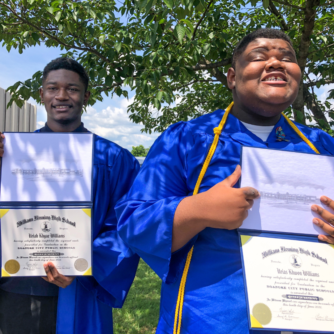 Uriah and Urias hold up their diplomas and smile at the camera