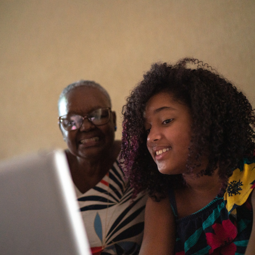 A woman and teen smile at a computer