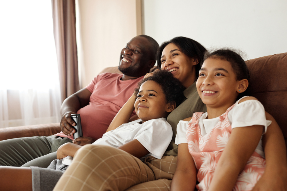 Family sits together on a coach and smiles