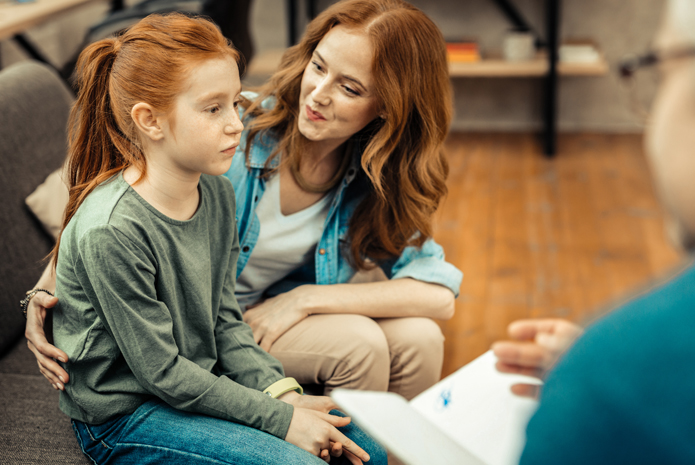 Young girl and her mother sit in a counseling session